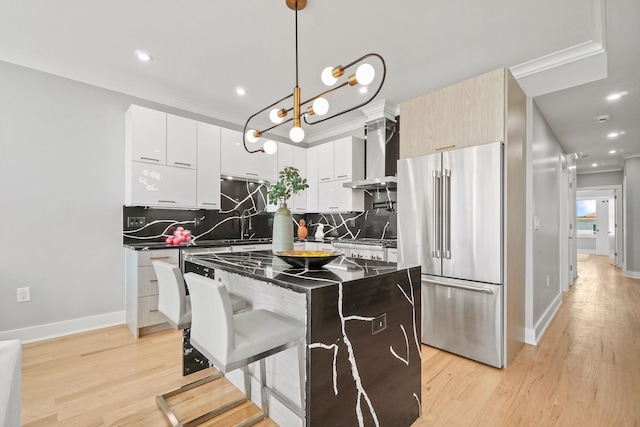 kitchen with pendant lighting, a center island, a kitchen breakfast bar, wall chimney exhaust hood, and high quality fridge