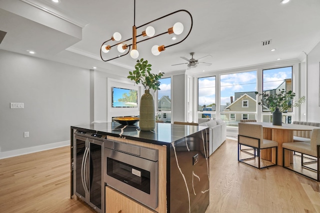 kitchen featuring ceiling fan with notable chandelier, a kitchen island, light wood-type flooring, and crown molding