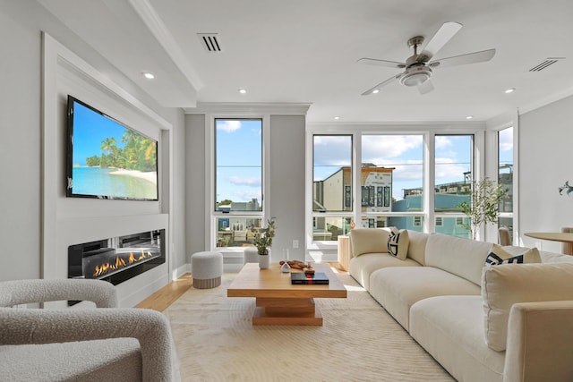 living room with ceiling fan, crown molding, and light wood-type flooring