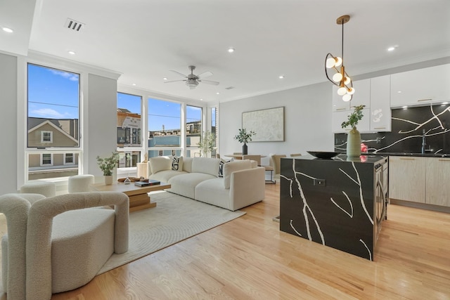 living room with ceiling fan, crown molding, and light hardwood / wood-style floors