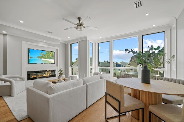 living room featuring ceiling fan, light hardwood / wood-style floors, crown molding, and expansive windows