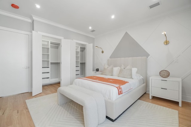 bedroom featuring hardwood / wood-style floors, a walk in closet, and crown molding