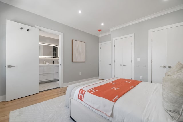 bedroom with connected bathroom, light hardwood / wood-style floors, and ornamental molding