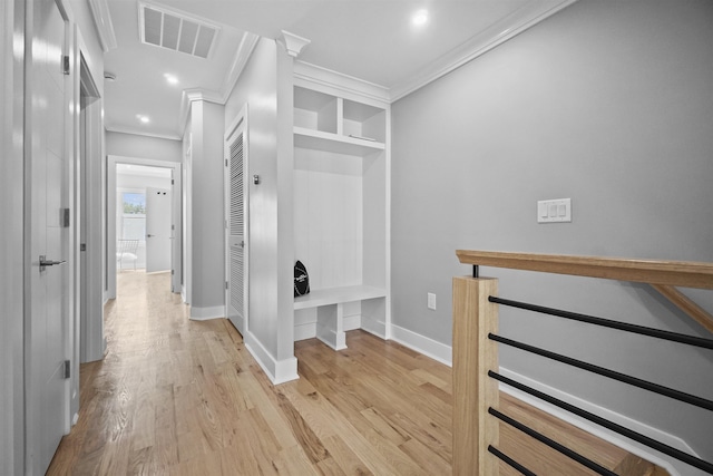 corridor with light hardwood / wood-style floors, built in features, and crown molding