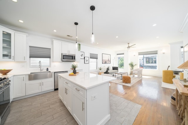 104 Poplar St Unit 1, Jersey City, NJ 07307 - kitchen with stainless steel appliances, crown molding, light wood-type flooring, white cabinetry, and a kitchen island