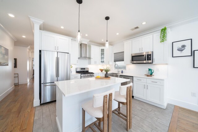 104 Poplar St Unit 1, Jersey City, NJ 07307 - kitchen with appliances with stainless steel finishes, wall chimney exhaust hood, light wood-style floors, ornamental molding, and a center island