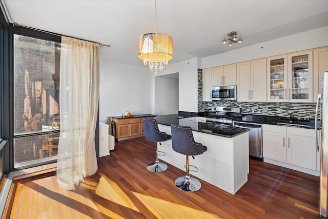 kitchen with sink, hanging light fixtures, a kitchen breakfast bar, backsplash, and appliances with stainless steel finishes