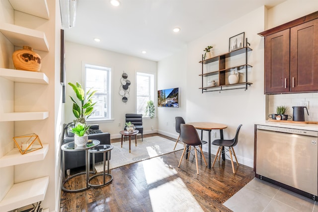 interior space featuring backsplash, stainless steel dishwasher, and light wood-type flooring