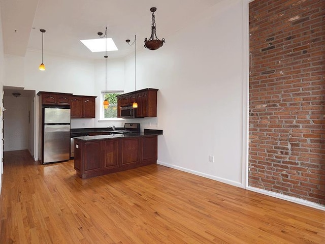 133 Lafayette St Unit 3R, Jersey City, NJ 07304 - kitchen featuring appliances with stainless steel finishes, a skylight, dark countertops, a peninsula, and light wood finished floors