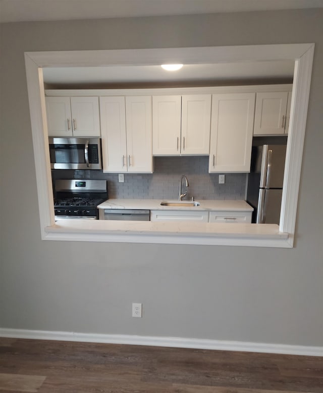 kitchen with tasteful backsplash, sink, white cabinetry, stainless steel appliances, and dark hardwood / wood-style flooring