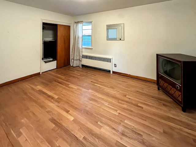 unfurnished bedroom with a closet, light hardwood / wood-style flooring, and radiator