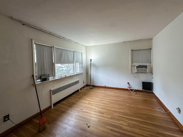 unfurnished living room featuring hardwood / wood-style floors, cooling unit, and radiator heating unit