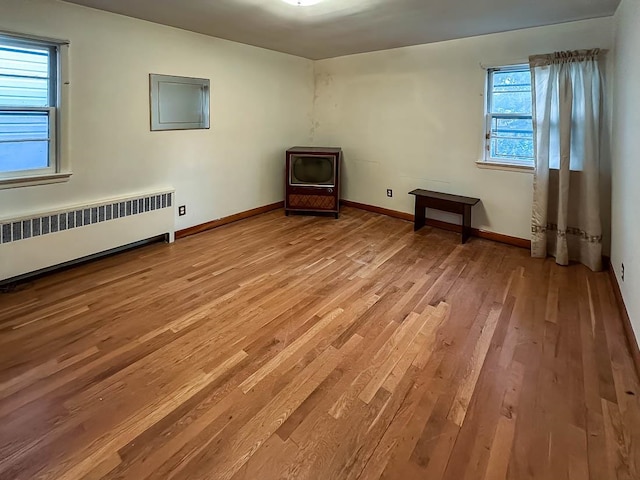 empty room featuring radiator and light hardwood / wood-style flooring