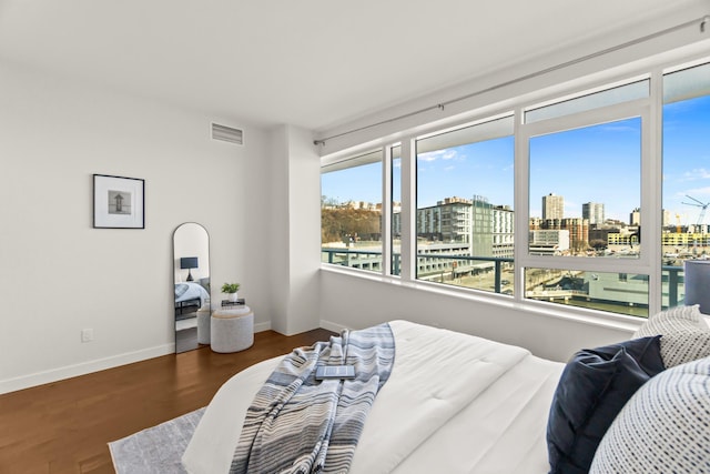 bedroom with baseboards, a view of city, visible vents, and wood finished floors