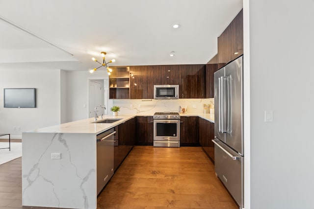 kitchen with a peninsula, a sink, appliances with stainless steel finishes, backsplash, and modern cabinets