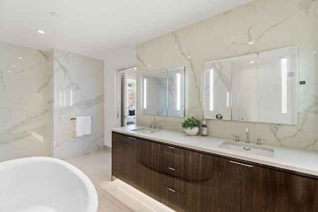 bathroom featuring a freestanding tub, double vanity, a sink, and stone wall