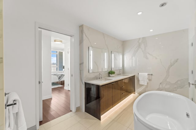 bathroom with a freestanding tub, tile walls, a sink, and ensuite bathroom