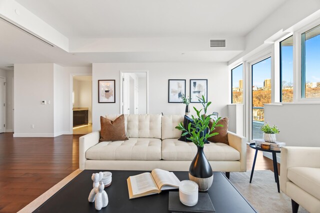 living area with baseboards, visible vents, and wood finished floors