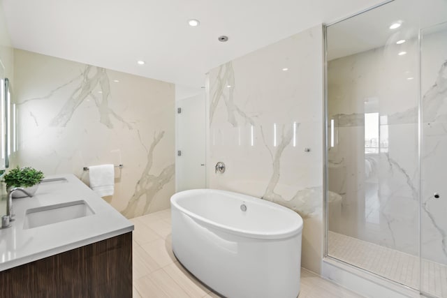 full bathroom featuring tile walls, a marble finish shower, recessed lighting, a soaking tub, and a sink