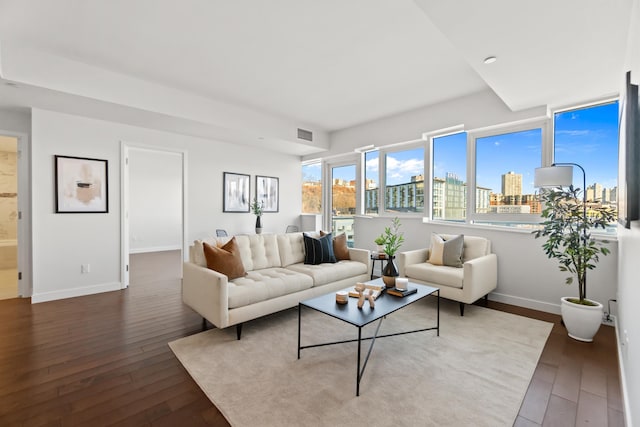 living room featuring baseboards, visible vents, a city view, and hardwood / wood-style floors