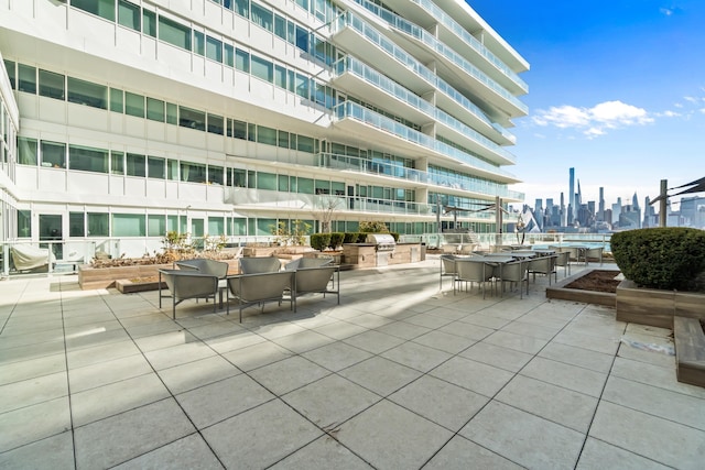 view of patio / terrace with exterior kitchen, outdoor dining space, a city view, and a grill