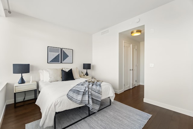 bedroom featuring wood-type flooring, visible vents, and baseboards