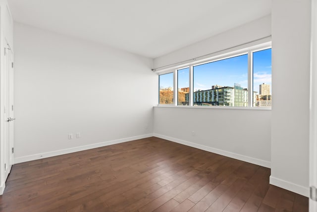 spare room featuring baseboards, wood finished floors, and a city view