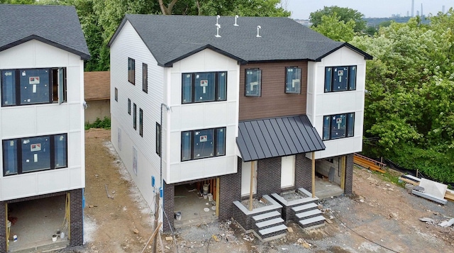 138 Weigands Ln, Secaucus, NJ 07094 - rear view of house with a shingled roof, a metal roof, and brick siding