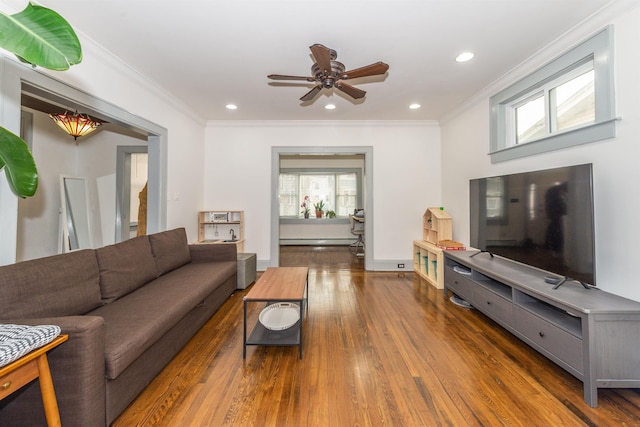 living room with recessed lighting, wood finished floors, baseboard heating, and ornamental molding