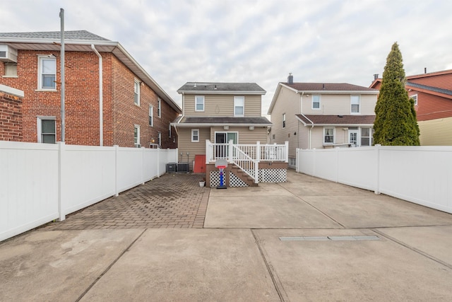 back of property with a patio, a fenced backyard, and central AC