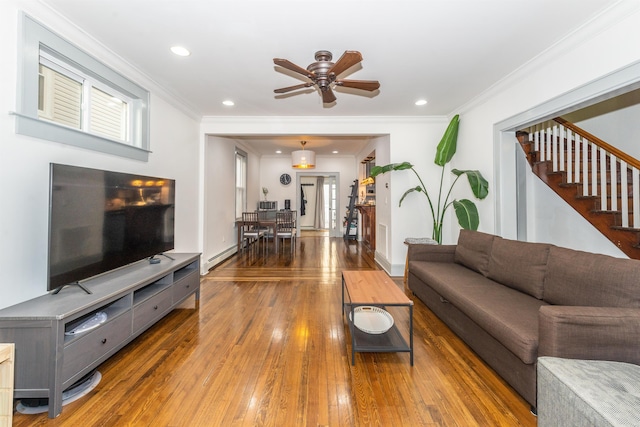 living area with hardwood / wood-style floors, a baseboard radiator, recessed lighting, stairs, and crown molding