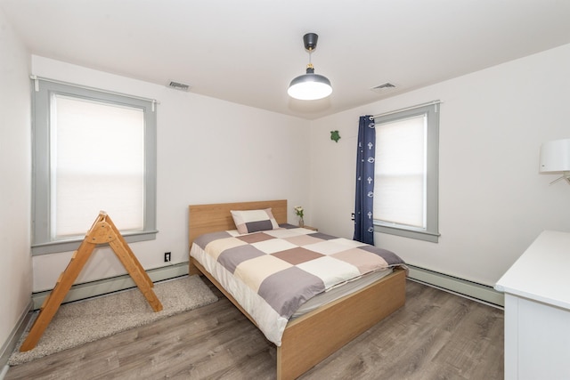 bedroom with visible vents, wood finished floors, and a baseboard radiator