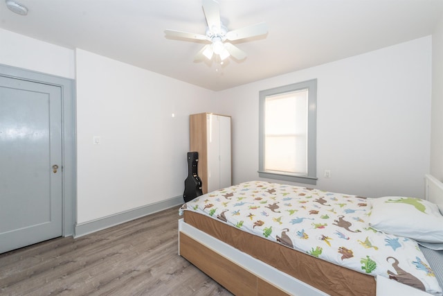 bedroom with baseboards, light wood-style flooring, and a ceiling fan