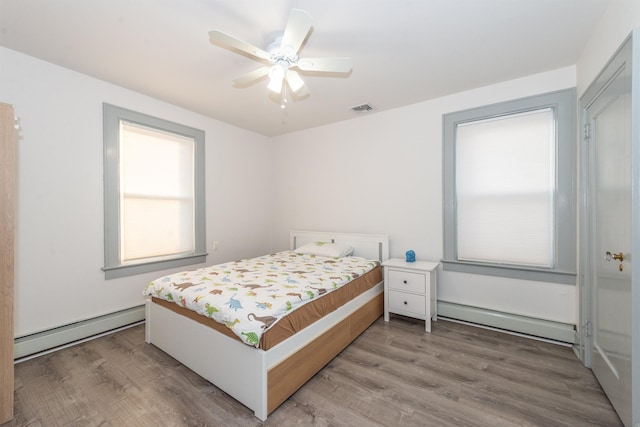 bedroom featuring visible vents, wood finished floors, and a baseboard radiator