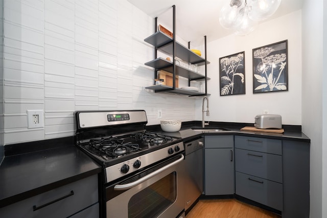 140 Bay St Unit 6E, Jersey City, NJ 07302 - kitchen with appliances with stainless steel finishes, dark countertops, gray cabinets, light wood-style floors, and a chandelier