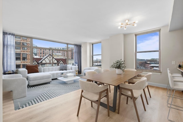 dining room featuring an inviting chandelier, light hardwood / wood-style floors, and a wall of windows