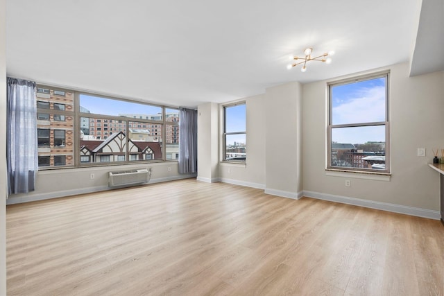 unfurnished living room featuring light hardwood / wood-style flooring, a notable chandelier, and a wall mounted AC