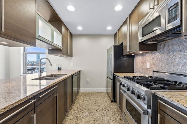 kitchen featuring sink, stainless steel appliances, light stone counters, and dark brown cabinetry