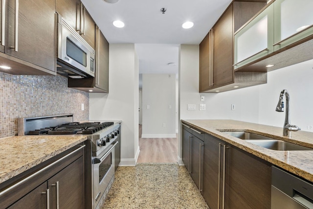 kitchen with appliances with stainless steel finishes, light stone counters, sink, and dark brown cabinetry