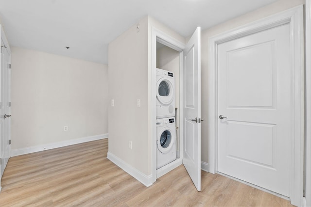 laundry area with stacked washer and dryer and light hardwood / wood-style flooring