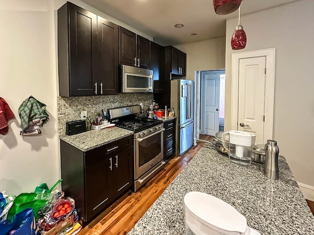 kitchen with stainless steel appliances, dark hardwood / wood-style floors, backsplash, and light stone counters