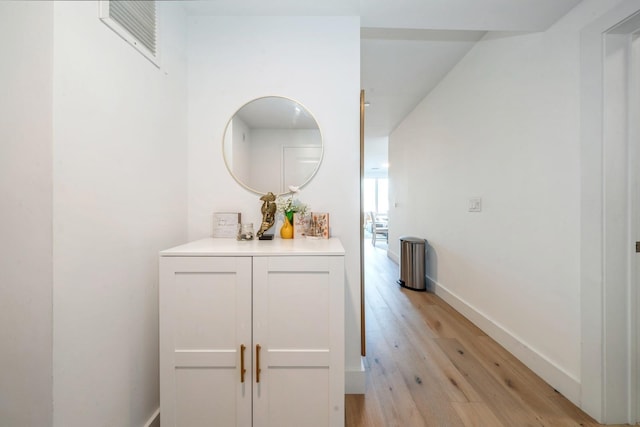 hall featuring light wood-style flooring and baseboards