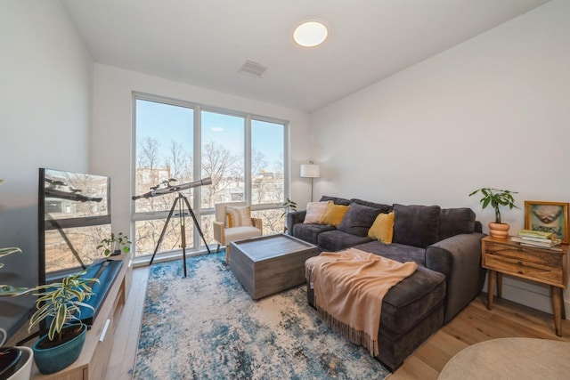 living area featuring visible vents and wood finished floors