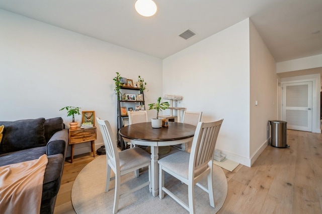 dining space featuring baseboards, visible vents, and light wood finished floors