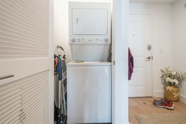 washroom with stacked washer / drying machine and wood finished floors