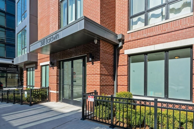 entrance to property featuring fence and brick siding