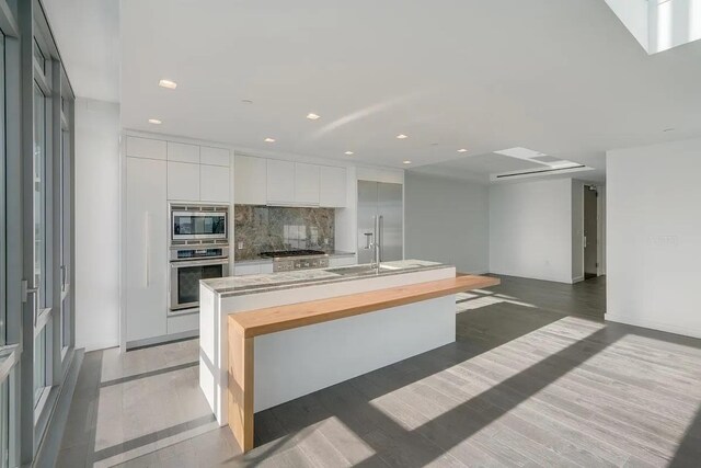 320 Adolphus Ave Unit 1415, Cliffside Park, NJ 07010 - kitchen with stainless steel appliances, modern cabinets, tasteful backsplash, a center island with sink, and white cabinetry