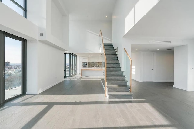 320 Adolphus Ave Unit 1415, Cliffside Park, NJ 07010 - unfurnished living room with a towering ceiling, stairway, wood finished floors, baseboards, and recessed lighting