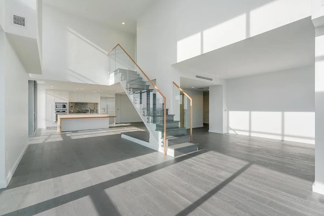 320 Adolphus Ave Unit 1415, Cliffside Park, NJ 07010 - unfurnished living room with a towering ceiling, baseboards, stairs, light wood-style flooring, and a sink