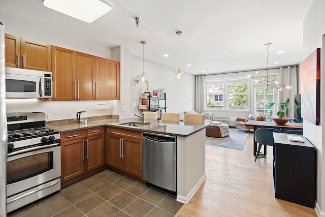 30 Freedom Way Unit 302, Jersey City, NJ 07305 - kitchen with appliances with stainless steel finishes, a peninsula, dark stone counters, brown cabinets, and pendant lighting
